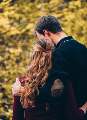 woman and man standing beside tree at daytime